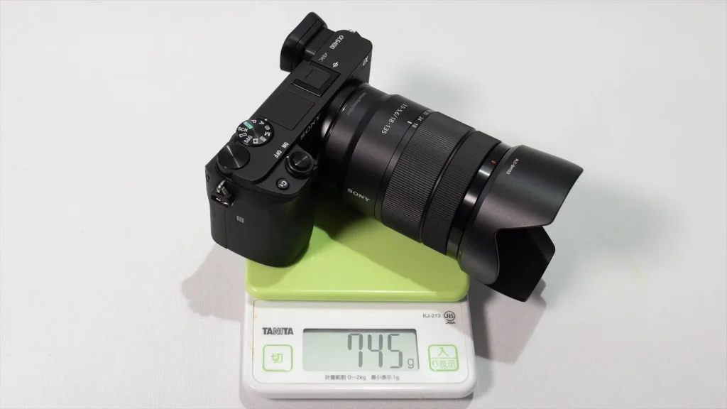 量りに乗せたE 18-135mm F3.5-5.6 OSS を装着したα6400 745g